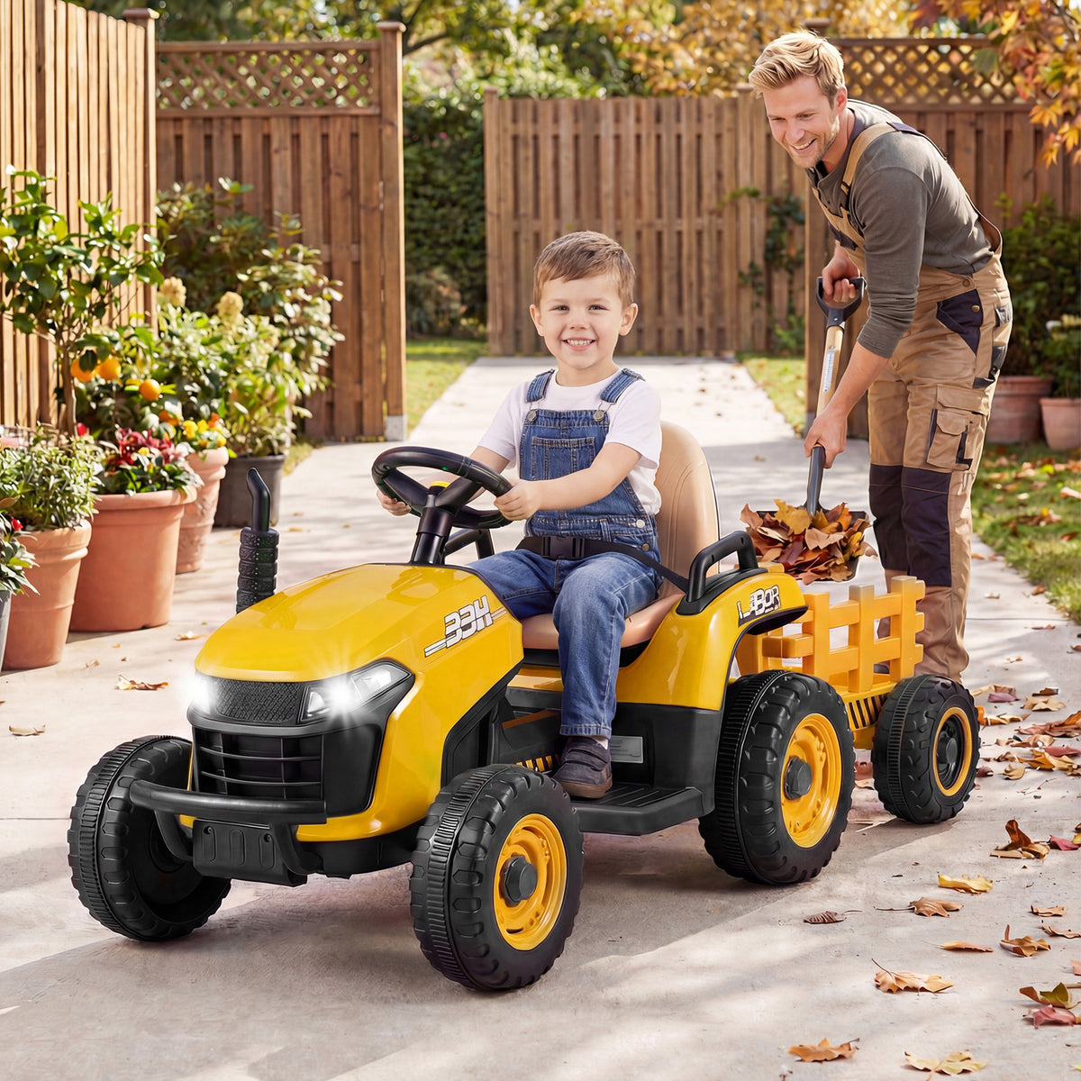 Young boy driving the kids electric tractor with trailer in a garden