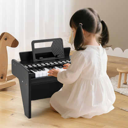 A young girl in a white dress playing the black wooden toy piano