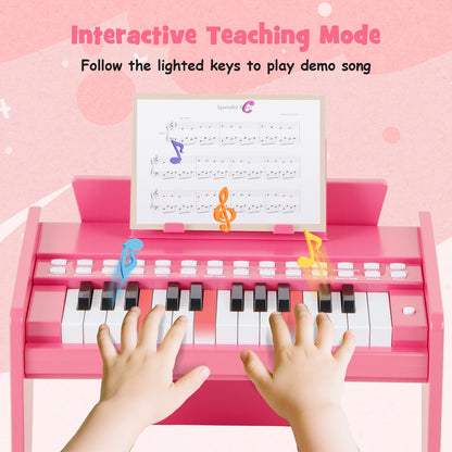 Hands playing the pink wooden toy piano with lighted keys