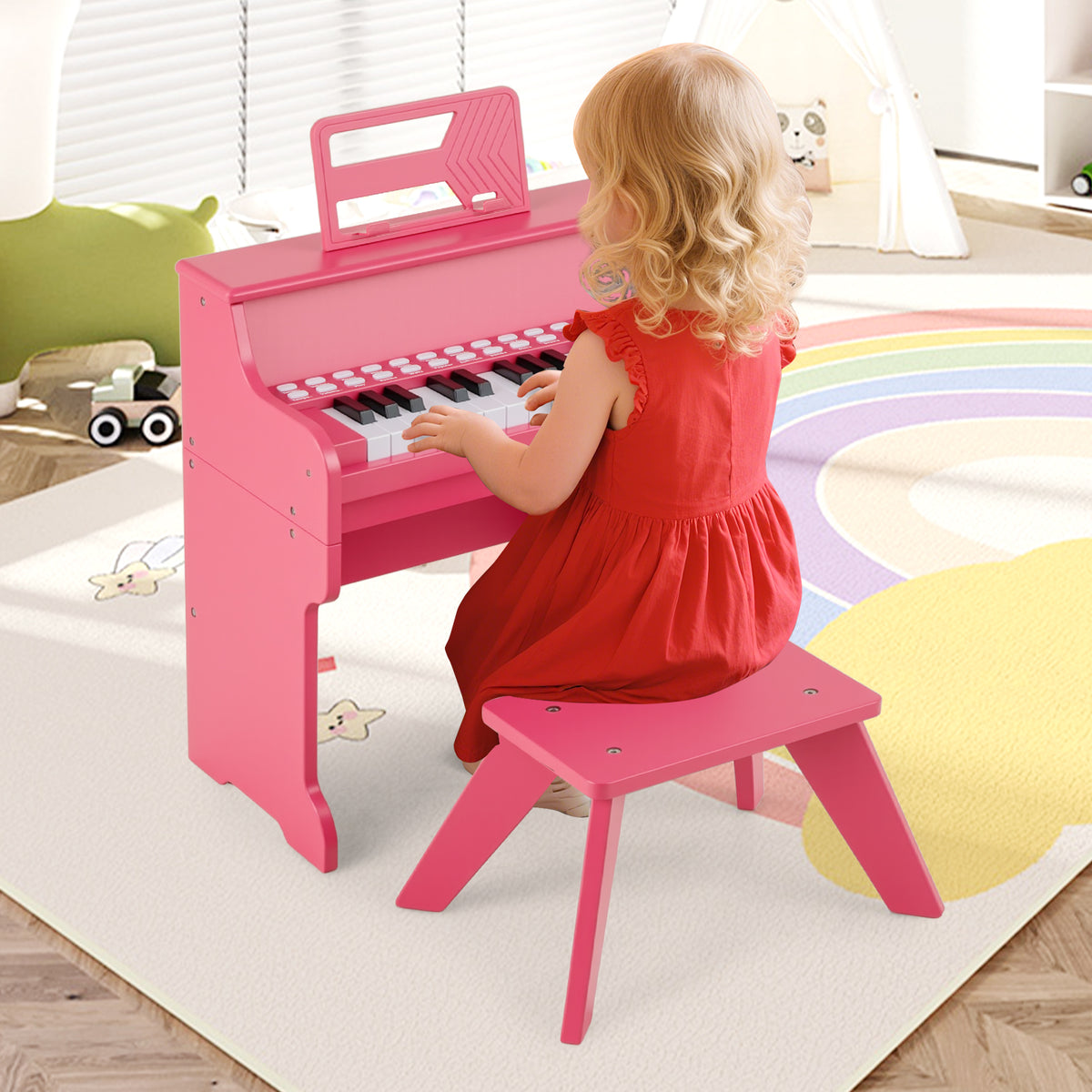 Young child in a red dress playing the pink kids piano keyboard with stool