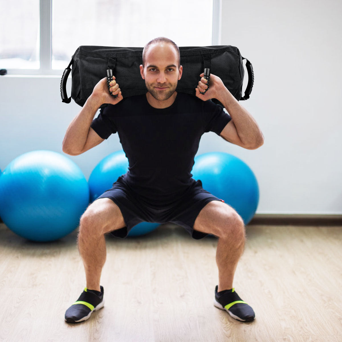 The training sandbag held on the shoulders of a man squatting in a bright room