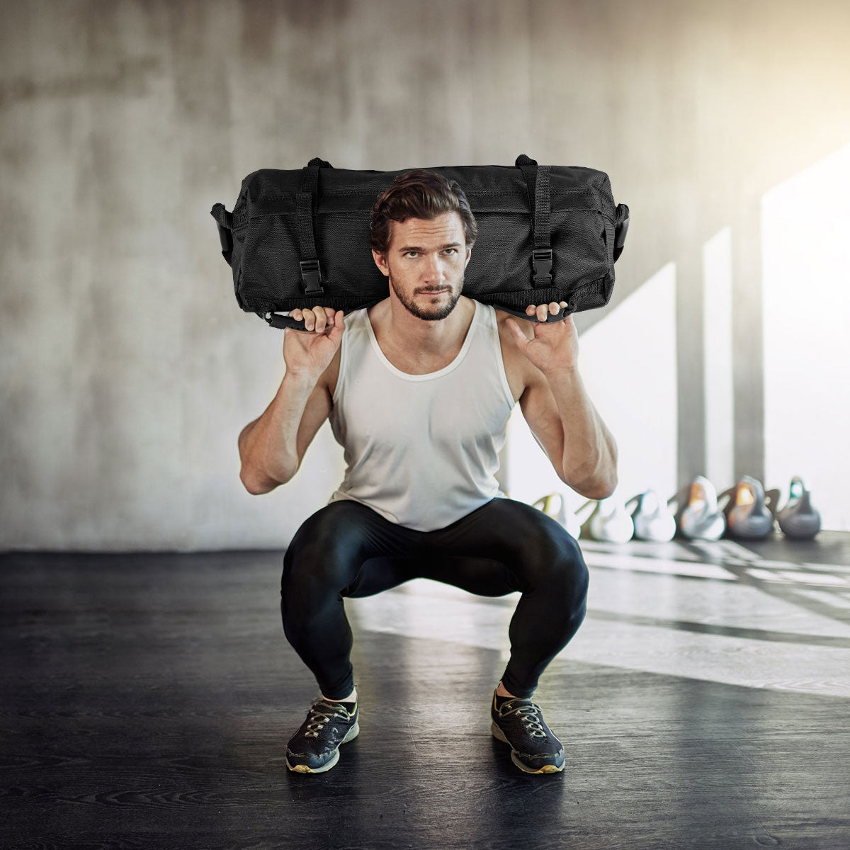 The training sandbag held on the shoulders of a man performing a squat in a gym