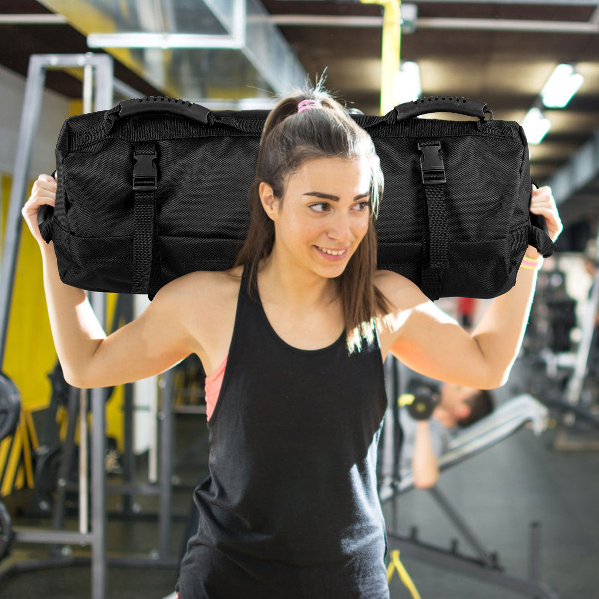 The training sandbag being held over the shoulders by a woman in a gym setting