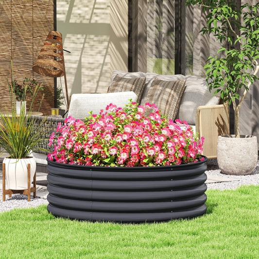 The raised planter box placed on a lawn in front of a patio seating area with vibrant pink flowers