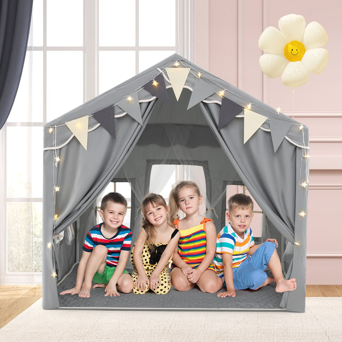 Four children sit happily inside the grey play tent house with star lights