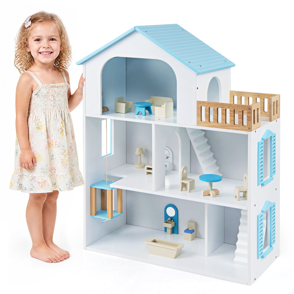 A young girl standing next to the wooden dollhouse playset