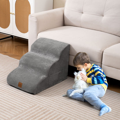 A child sits on the floor next to a grey foam dog ramp, petting a small dog
