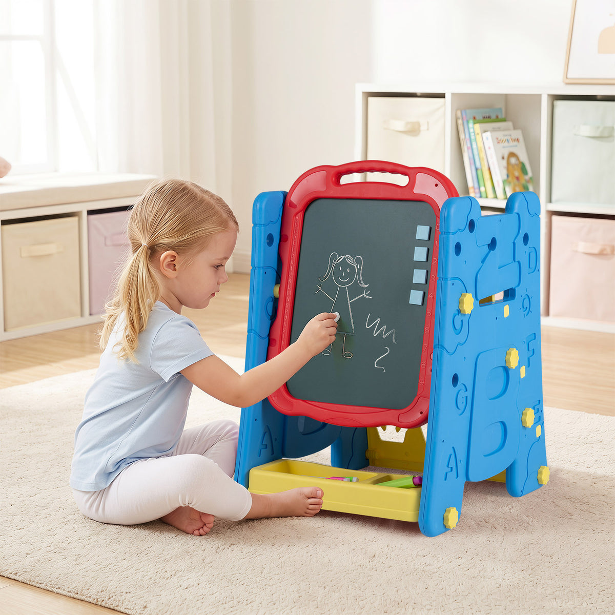 Young girl drawing on the chalkboard of the art easel