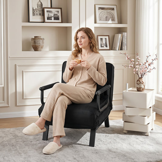 The black sofa chair placed in a bright living room with a woman sitting and holding a cup