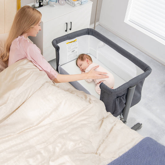 The bedside sleeper placed next to a bed with a mother watching her sleeping baby