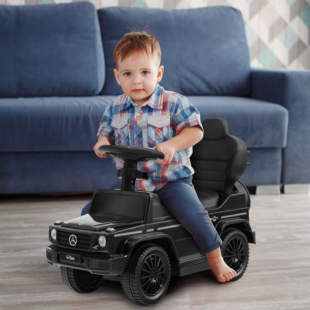 Toddler sitting in the black sliding walker with push handle, steering the wheel