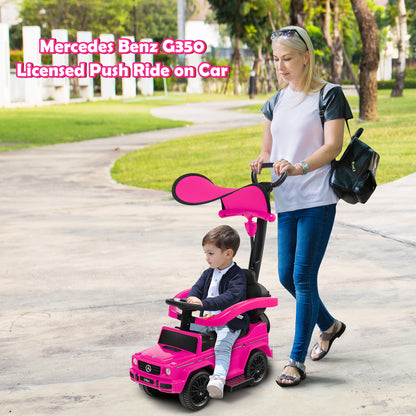 A woman pushes a baby in the pink ride-on toy car down a path