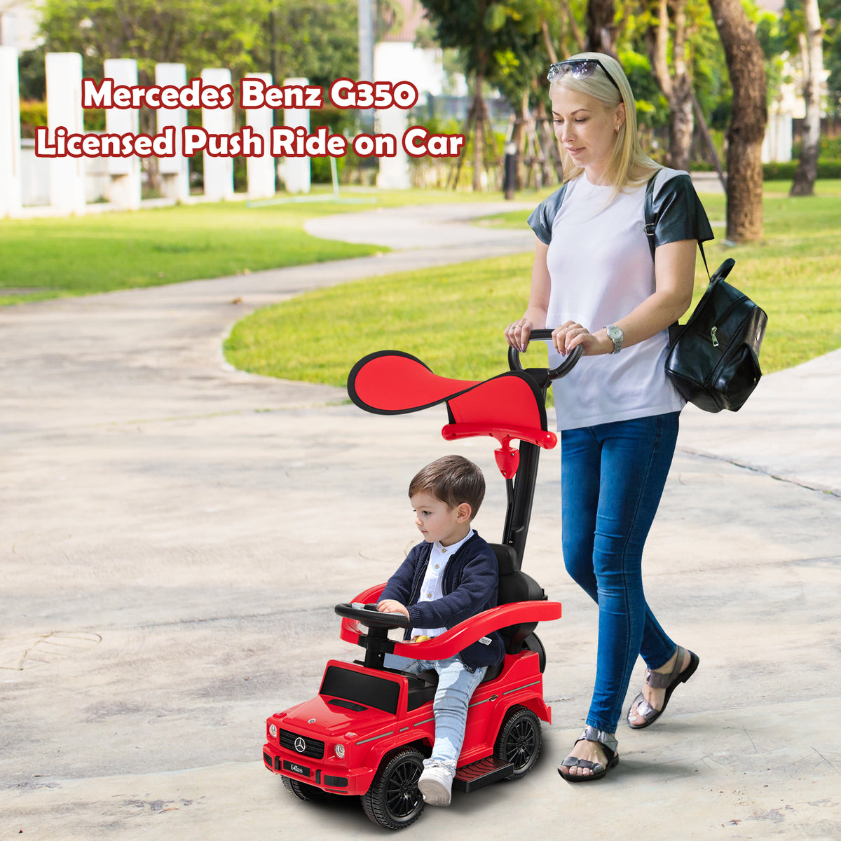 A woman pushes the red baby walker with a toddler inside on a path