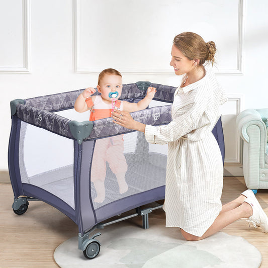 The grey convertible bassinet cot with a baby inside and a woman kneeling beside it