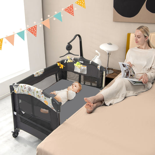 The bedside sleeper positioned next to a bed with a baby resting inside while a woman reads