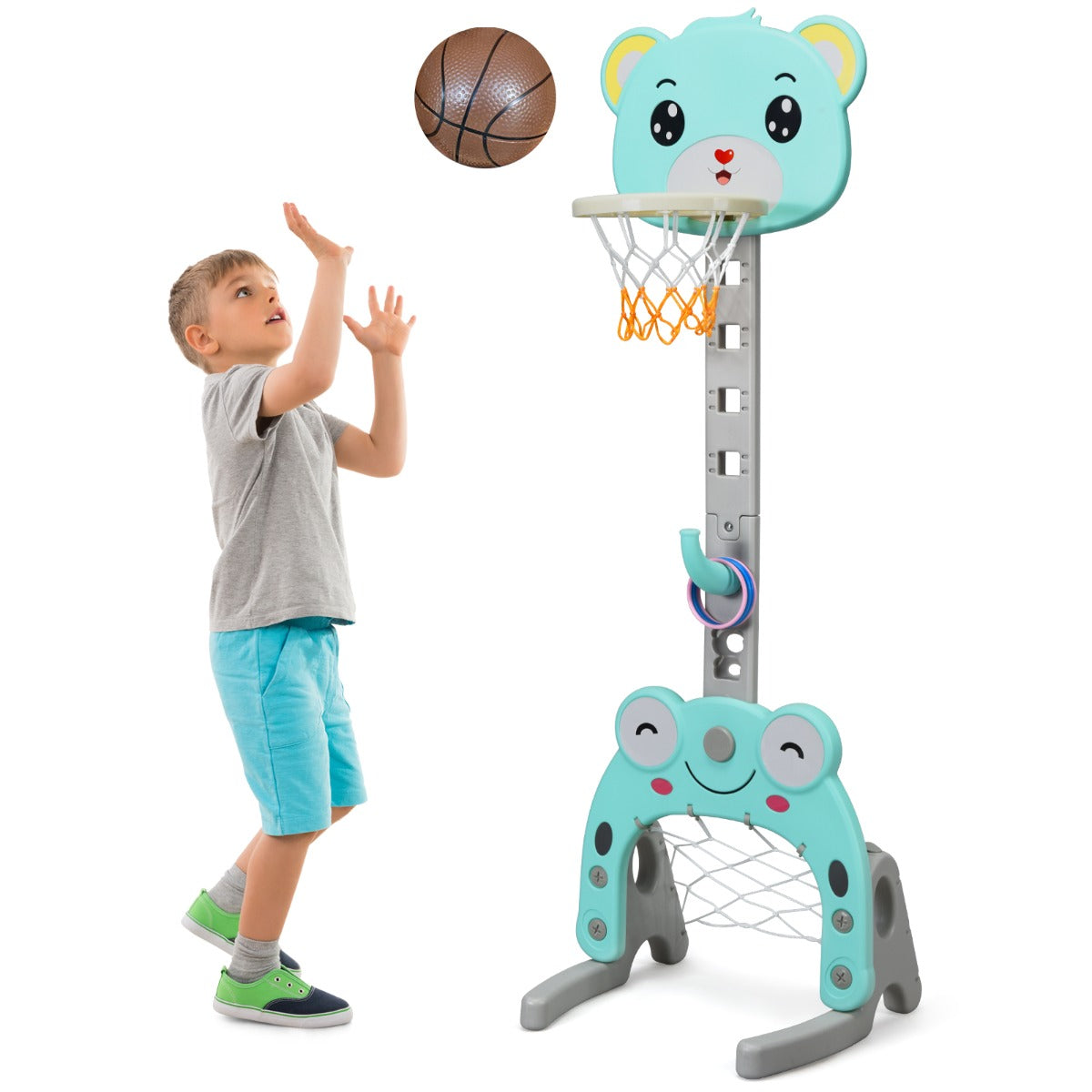 Boy throwing a basketball at the green toy sports hoop and stand set