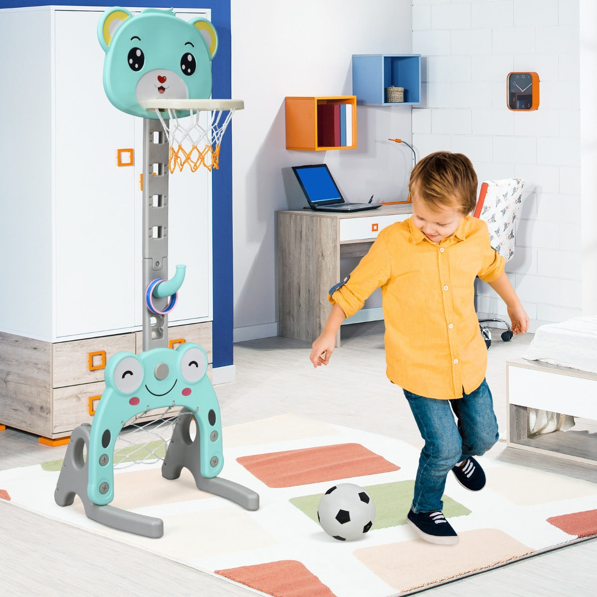 Boy playing football with the green toy sports hoop and stand set in a bedroom