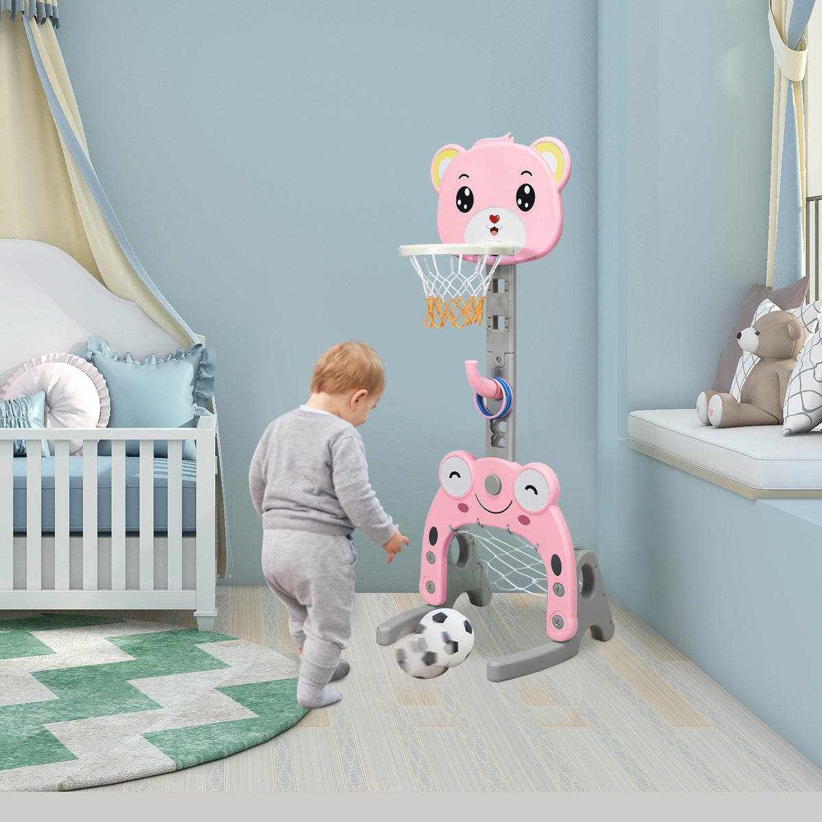 The pink 3 in 1 kids basketball hoop and stand set with a baby playing with a football