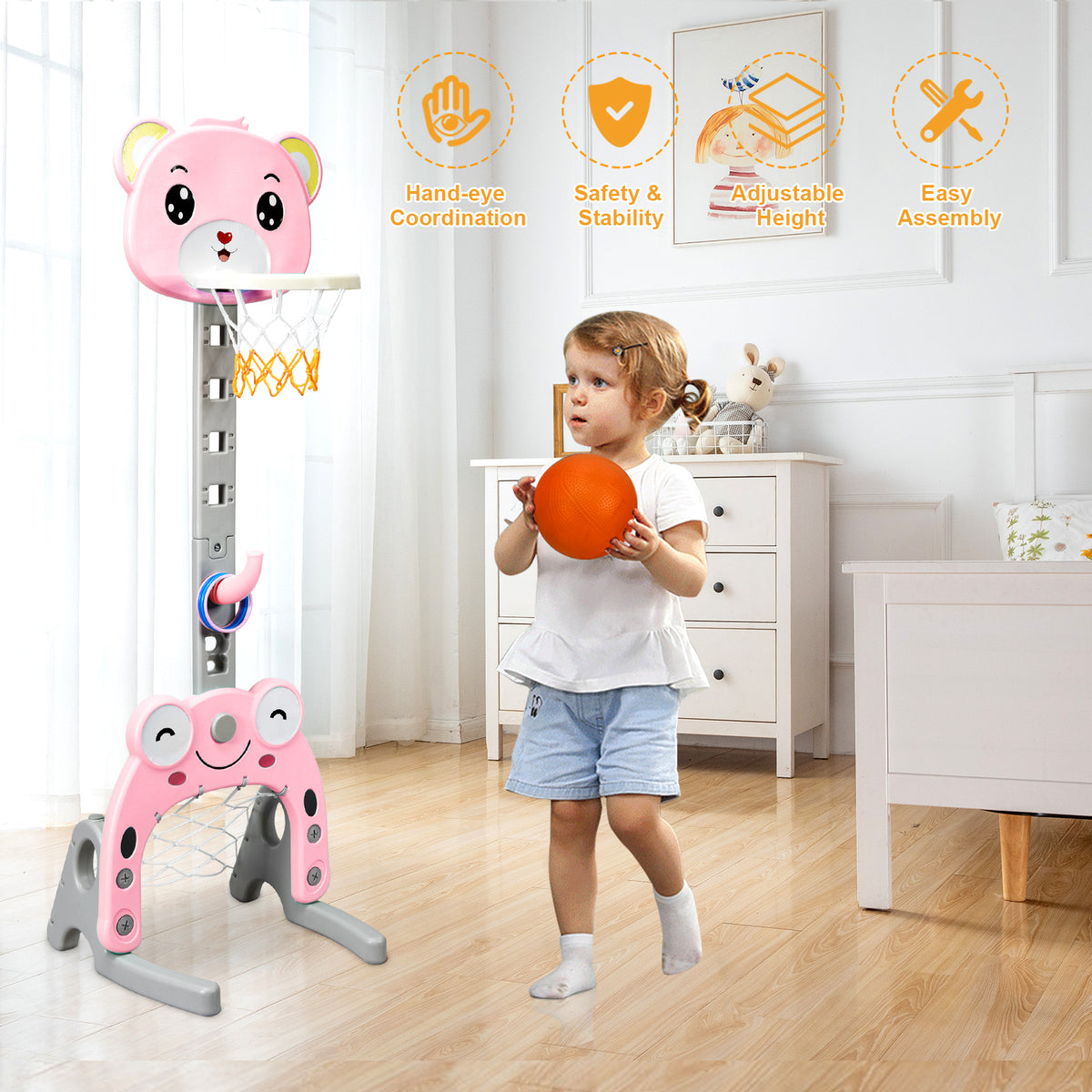 A young child holding a basketball next to the pink toy sports set