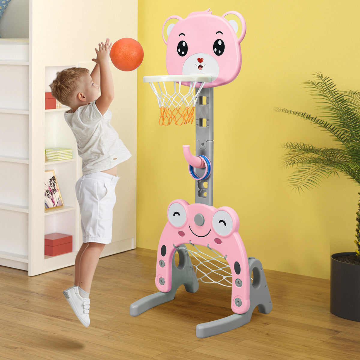 The pink kids basketball hoop and stand set with a boy playing basketball indoors