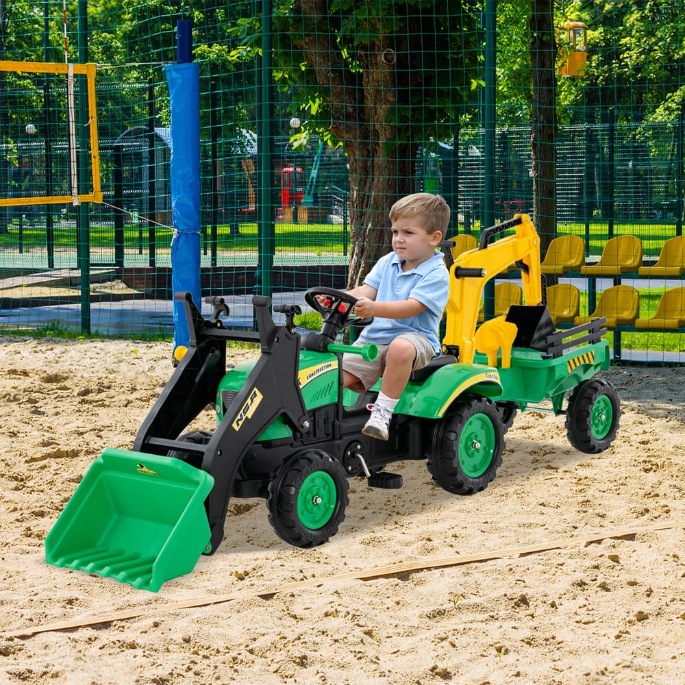 Child operating the green ride on excavator with trailer on a sandy playground