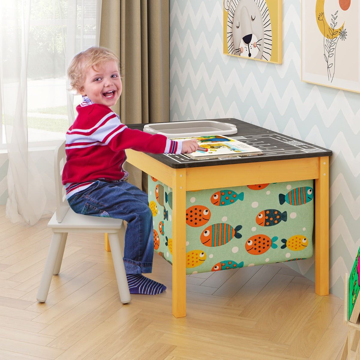Smiling toddler sitting at the kids sand water activity table in a bright room