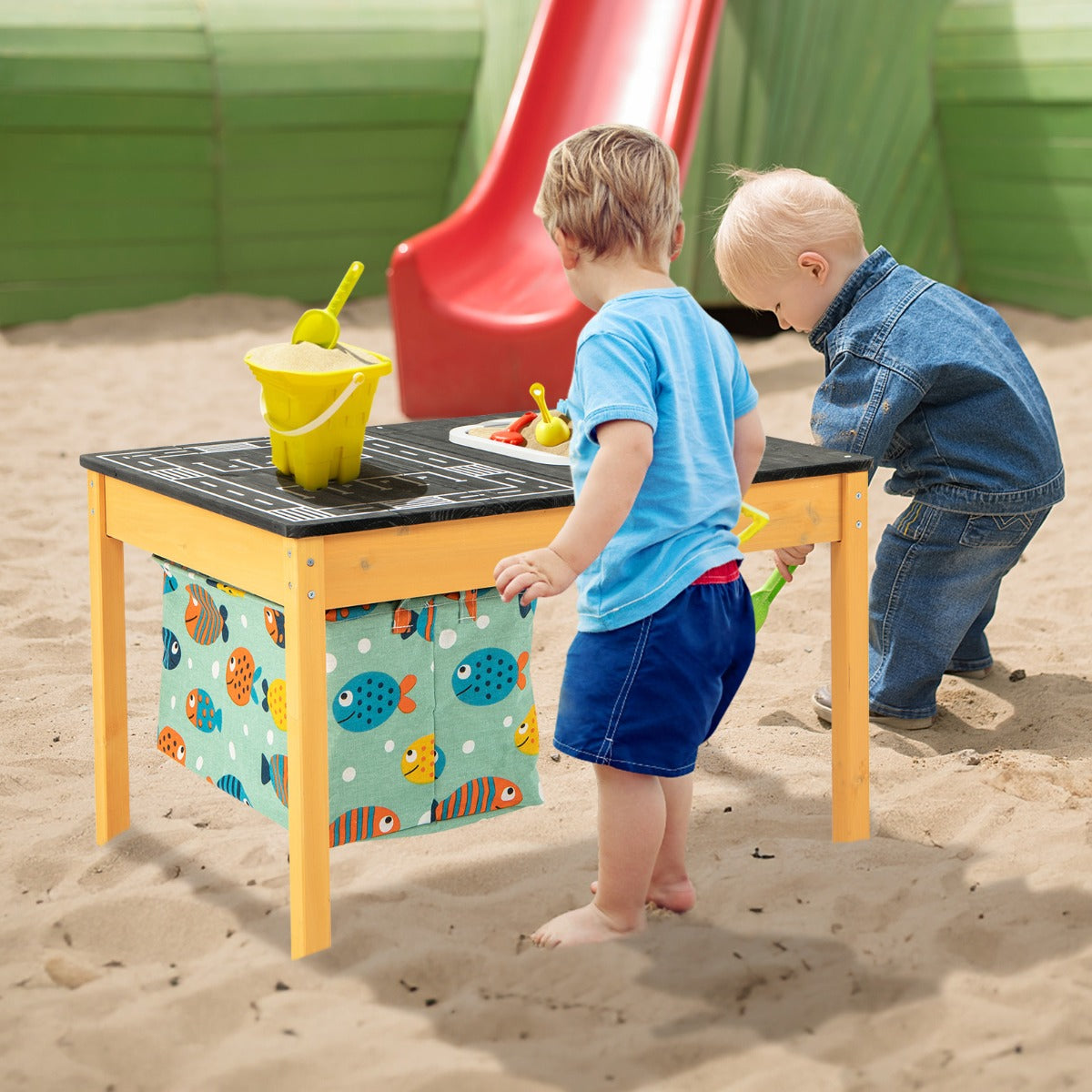 Two young children playing with the sand water activity table in a sandy outdoor area