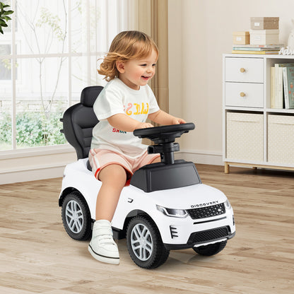 A toddler sits in the white ride on toy, steering and smiling