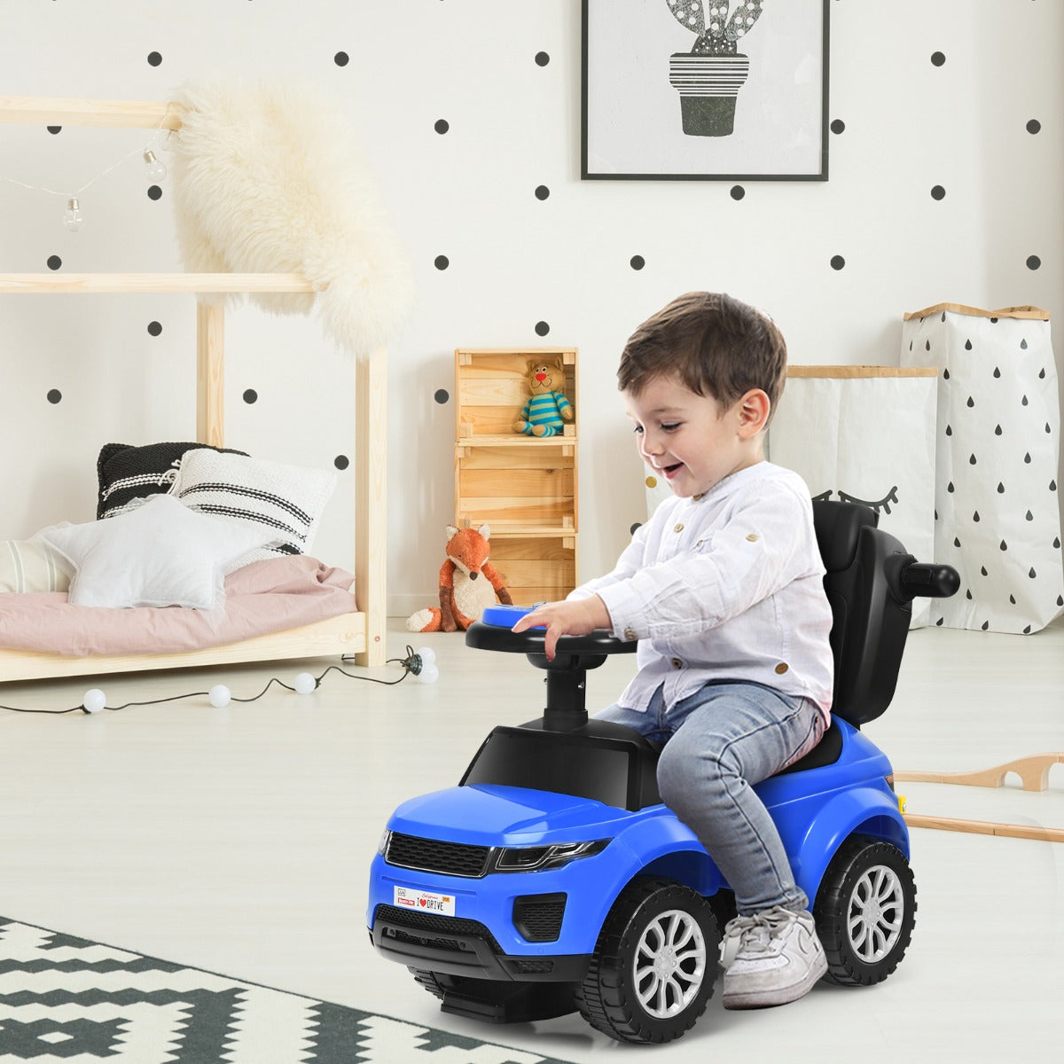 Child sitting on a blue ride on push car stroller in a child's bedroom