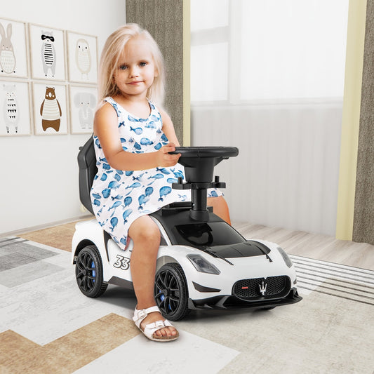 Little girl sitting on the white push car in a room