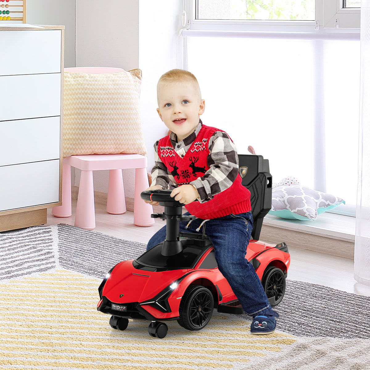 A red ride on push car with a child sitting in it, in a room