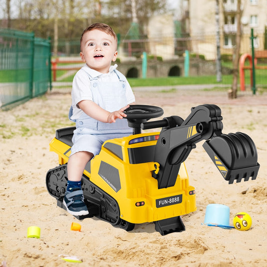 The yellow kids electric car being used by a toddler in a sandy outdoor play area