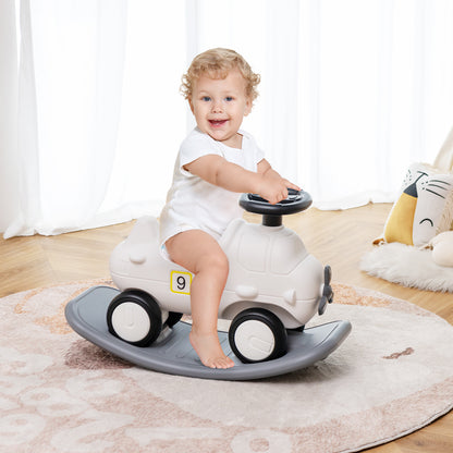 Baby smiling while sitting on the white rocking horse and sliding car