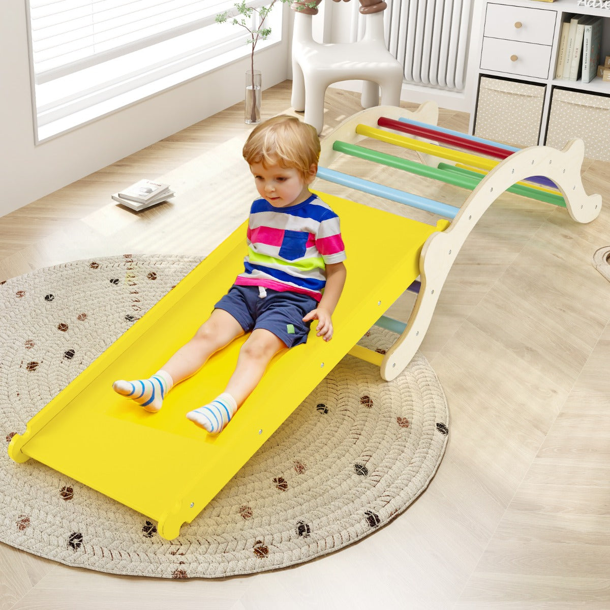 A young boy sliding down the yellow ramp of the wooden climbing arch