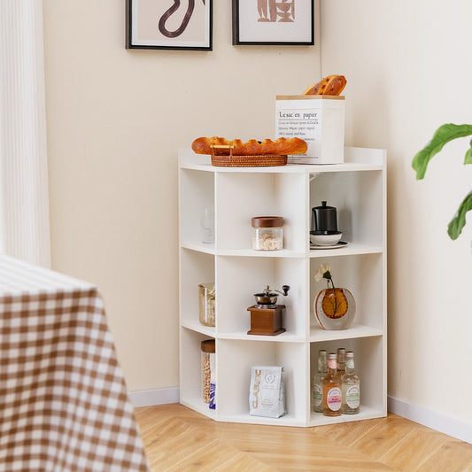 The white corner cabinet placed in a room corner with decorative items on the shelves