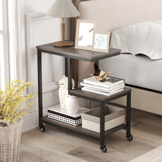 The side table placed next to a bed with a lamp, photo frames and storage boxes on its shelves