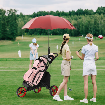 Two women using the golf cart on a course with a pink golf bag and red umbrella