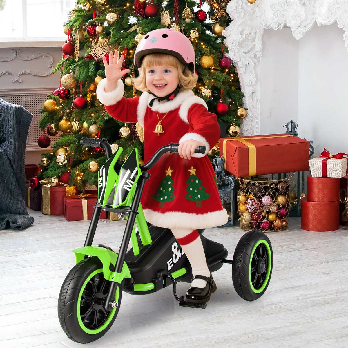 A young girl riding the toddler bike indoors next to a decorated Christmas tree