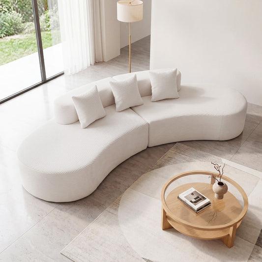 The white curved sectional sofa in a bright living room with a coffee table and lamp