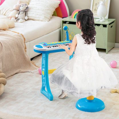 A girl in a white dress sitting on the stool playing the kids electronic keyboard