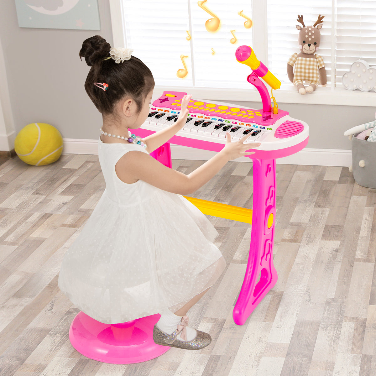 Young girl in a white dress playing the pink electronic keyboard with stool in a bright room
