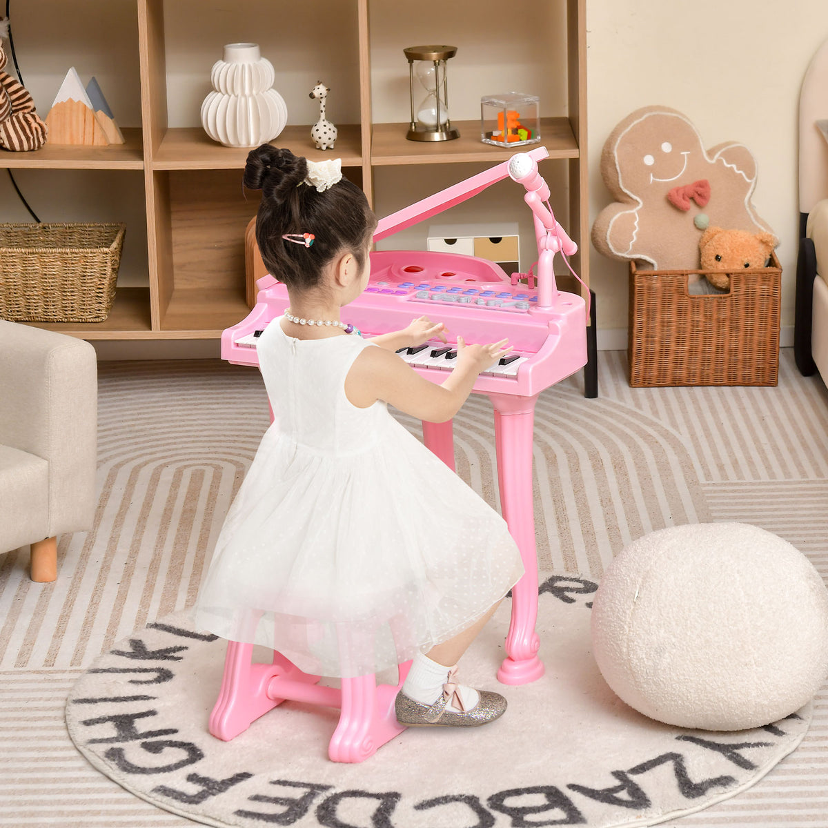 A young girl in a white dress plays the pink toy piano with microphone and stool in a decorated room