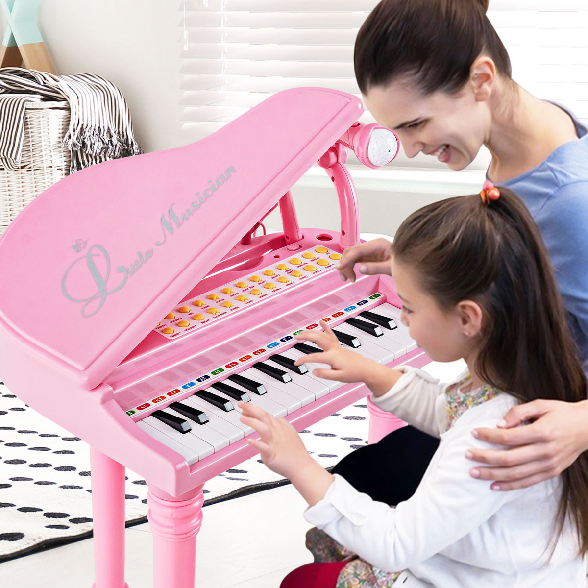 A mother and daughter play the pink toy piano together with the microphone