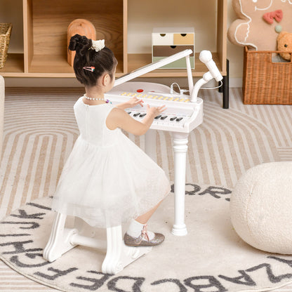 A young girl in a white dress plays the toy piano with microphone in a nursery