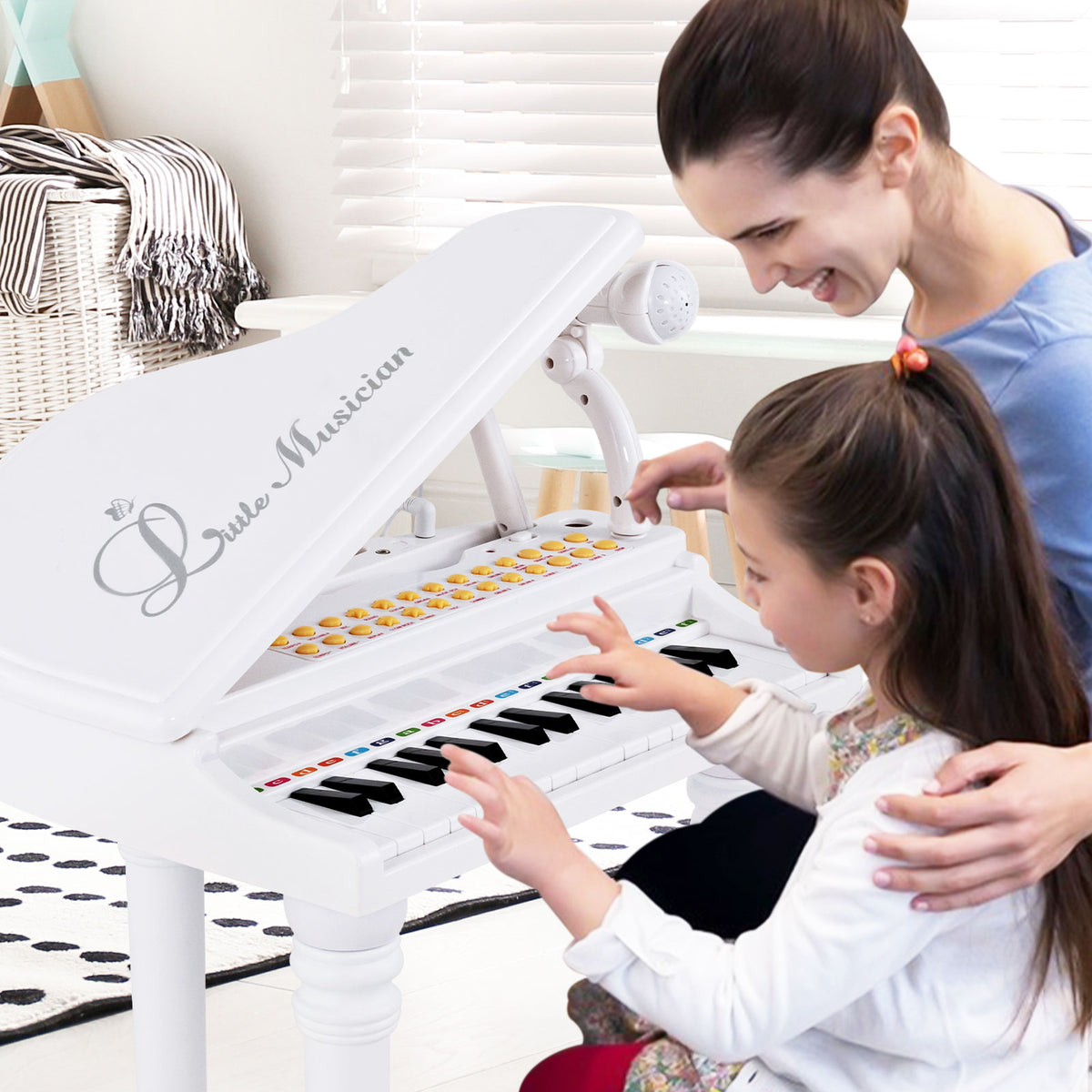 A mother and daughter play the white toy piano together in a living room setting