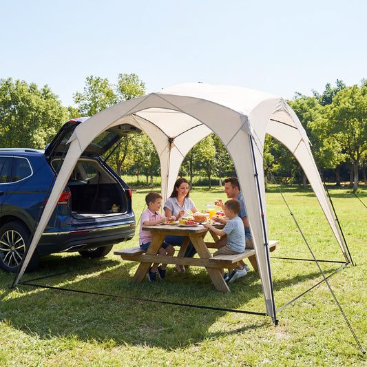 A family having a picnic under the pop up camping tent next to a car