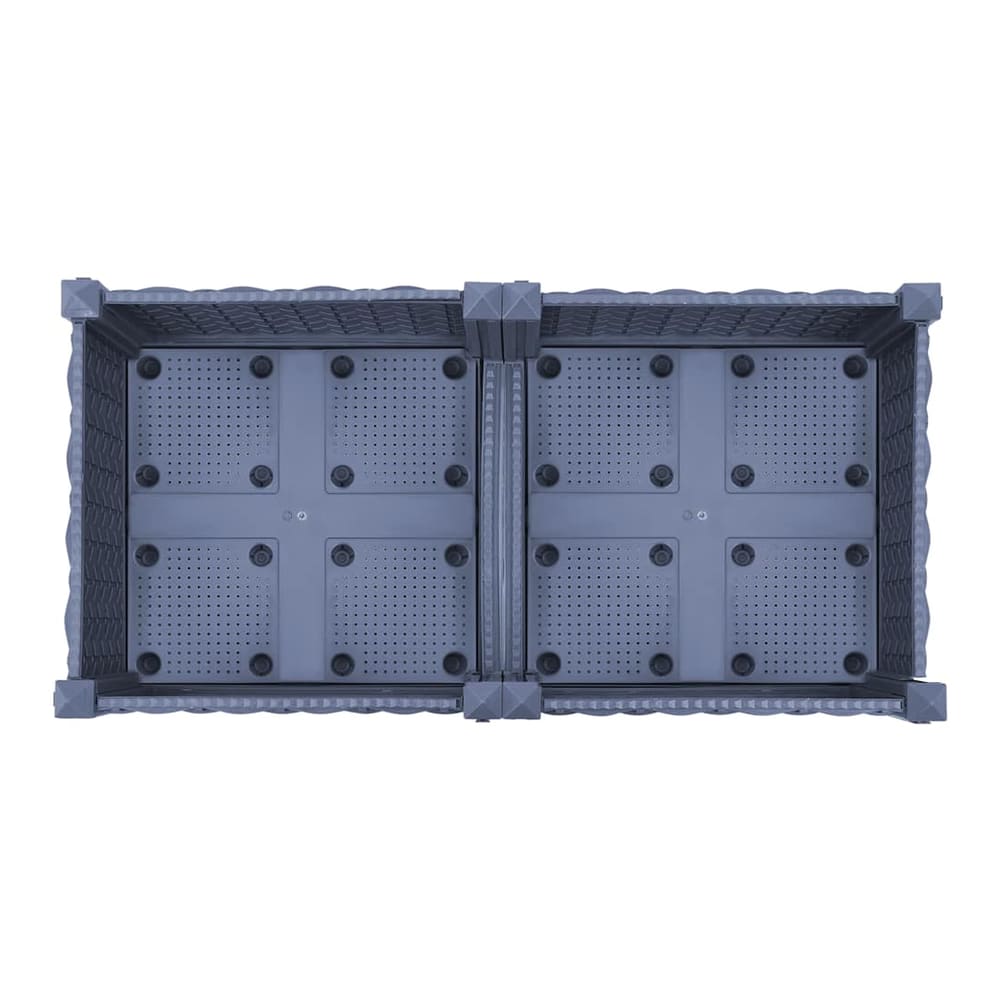 The base of a grey raised garden bed, showing drainage holes and construction