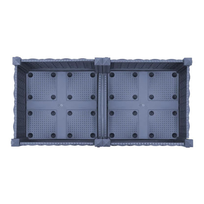 The base of a grey raised garden bed, showing drainage holes and construction