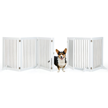 A small dog stands in front of the open door of the white wooden pet gate
