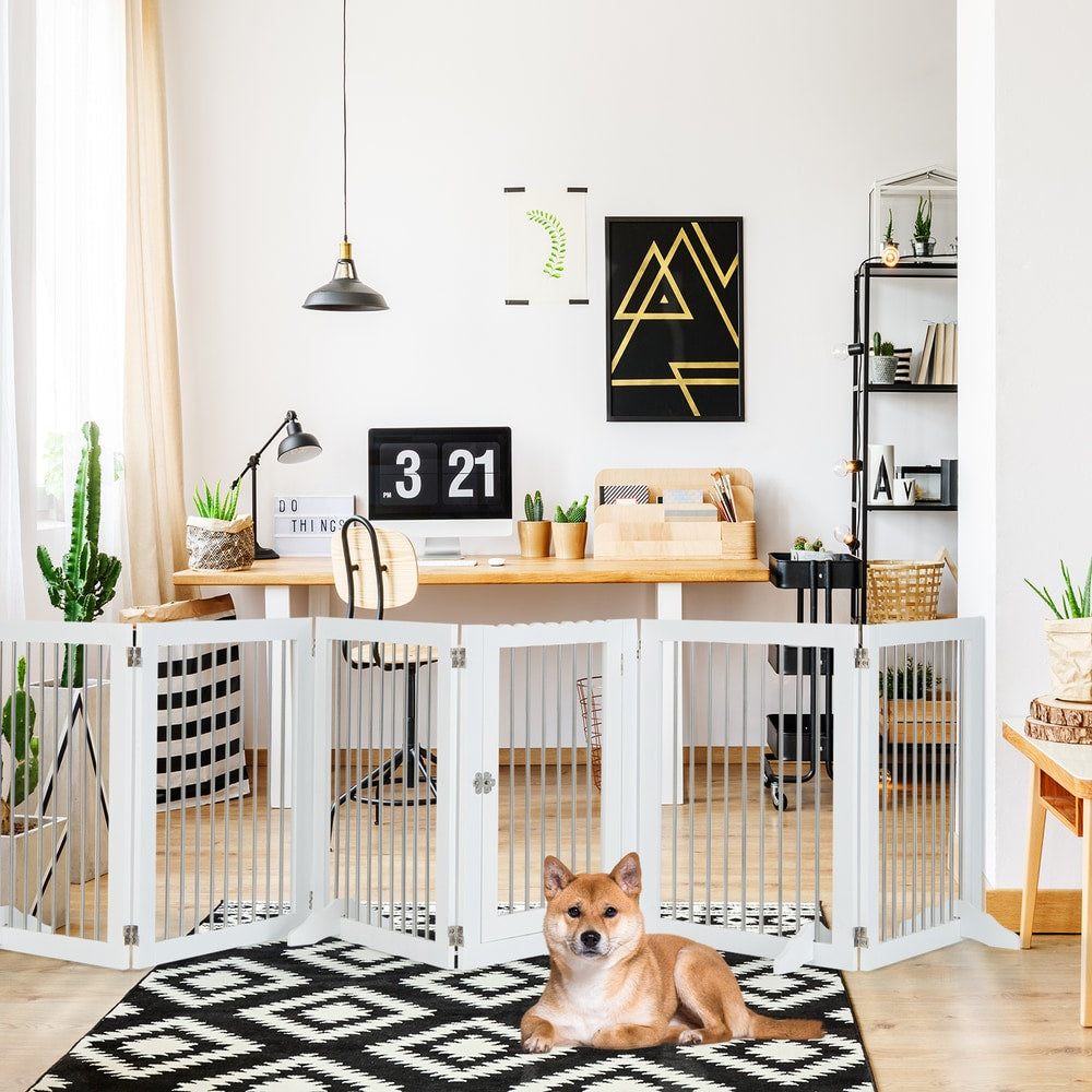 The white wooden pet gate is set up in a home office with two dogs resting nearby
